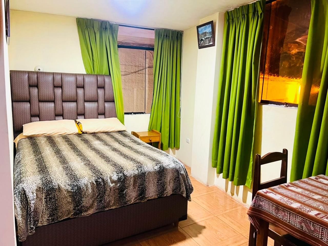 A bedroom with a bed, a nightstand, a chair, and a window with curtains.