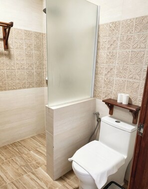 Une salle de bain avec une douche, des toilettes et une étagère contenant des articles de toilette.
