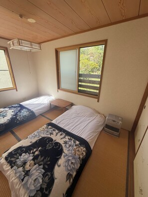 Ein Zimmer mit zwei Betten, einer Heizung und einem Fenster mit Blick auf Grünflächen.