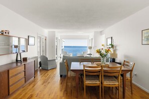 Un espace repas avec vue sur la mer, des meubles en bois et un grand miroir.