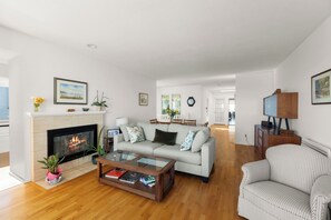 Un salon moderne avec une cheminée, un canapé, une table basse et un téléviseur posé sur un meuble en bois.