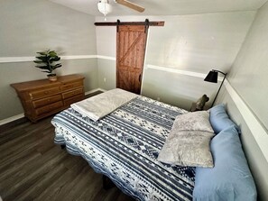 Ein Schlafzimmer mit Bett, Schminktisch, Pflanze und Deckenventilator.