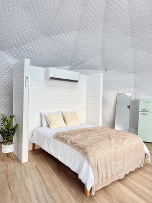 Une chambre à coucher avec un lit, une table de chevet, une plante en pot et une armoire.
