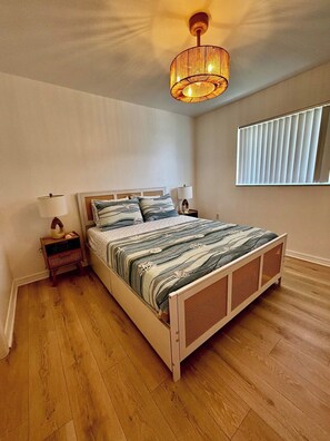 Una camera da letto con un letto di legno, un comodino, una lampada, una finestra con persiane e un lampadario.