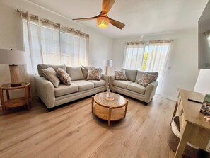 A living room with a sectional sofa, a round coffee table, and a ceiling fan. - Bradenton Beach Escape | Steps from Beach&Trolley (Bradenton Beach)