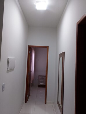 A narrow hallway with a ceiling light, a door frame, and a wall-mounted electrical outlet. - New Listing (Cabo Frio)