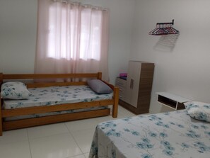 A bedroom with two beds, a wardrobe, a desk, and a hanging rack. - New Listing (Cabo Frio)