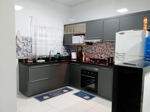A modern kitchen with grey cabinets, a black countertop, a built-in oven, and a refrigerator. - New Listing (Cabo Frio)