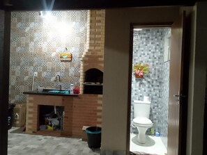 Ein Badezimmer mit gefliestem Rückspritzbereich, einem Waschbecken, einer Toilette und einer kleinen Ablagefläche.