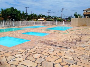 Ein Poolbereich mit mehreren rechteckigen Pools und einer terrasse mit Steinplatten.