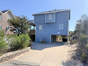 Ein zweistöckiges Wohngebäude mit Garage und überdachter Terrasse, strahlend blauer Himmel.