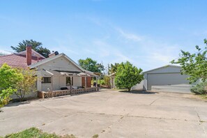 Une propriété résidentielle dotée d’un patio couvert, d’un garage et d’un petit arbre.