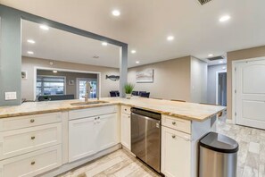 A modern kitchen with a large island, built-in dishwasher, and a trash can. - Tropical Paradise! Pool, Hot Tub & Outdoor Bar just minutes away from AMI! (Bradenton)