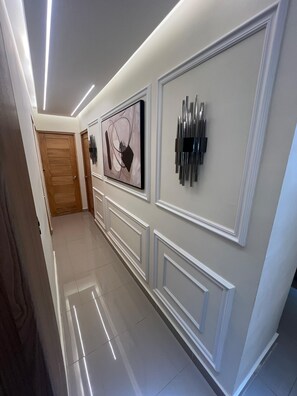 A hallway with a wooden door, a framed abstract painting, and a modern light fixture. - New Listing (Boca Chica)