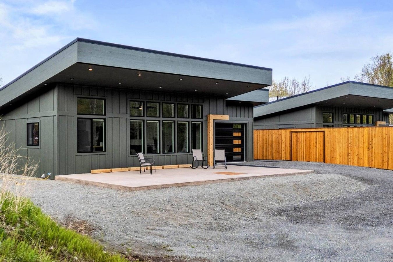 A modern two-story building with a flat roof, large windows, and a covered outdoor seating area.
