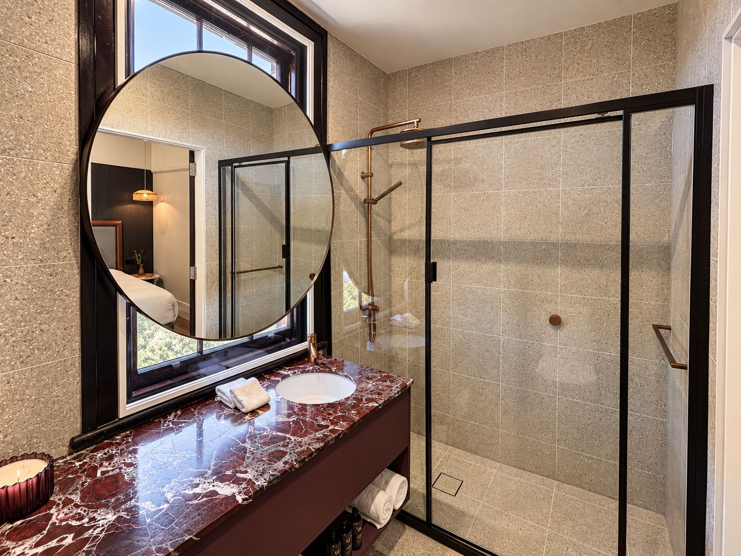 A modern bathroom with a glass-enclosed shower, a marble vanity, and a large mirror.