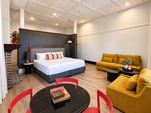 A modern hotel room with a bed, sofa, and a dining table with chairs. - Hotel Leichhardt (Leichhardt)