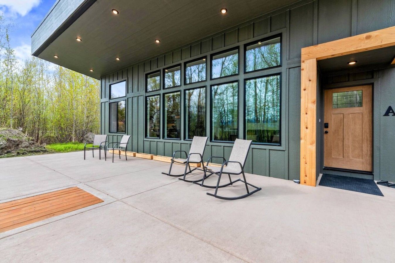 A building exterior with a covered patio area, large windows, and outdoor seating.