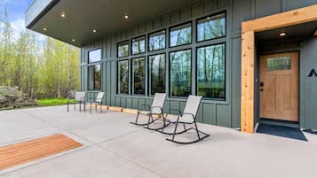 A building exterior with a covered patio area, large windows, and outdoor seating.