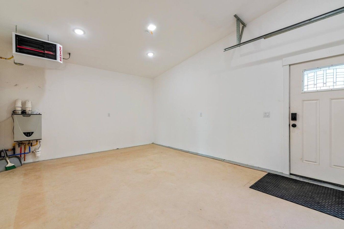 A room with a white door, a radiator, and a thermostat on the wall.
