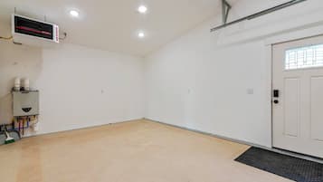 A room with a white door, a radiator, and a thermostat on the wall.