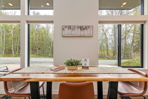 Un comedor con una mesa de madera, sillas de cuero, una planta pequeña y una obra de arte enmarcada en la pared.