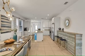 A modern kitchen with a central island, bar stools, and a dining area with a table and chairs.