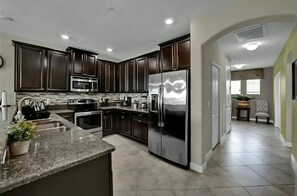 A modern kitchen with dark wood cabinets, stainless steel appliances, and a granite countertop.