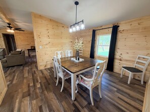 Interior de madeira com uma mesa de jantar, cadeiras e um ventilador de teto.