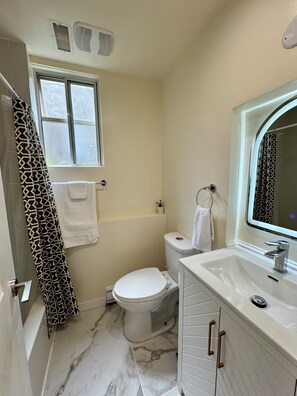 A bathroom with a toilet, sink, and window. - Spacious 3‑Bedroom Suite Near Grouse & Capilano-NV (North Vancouver)