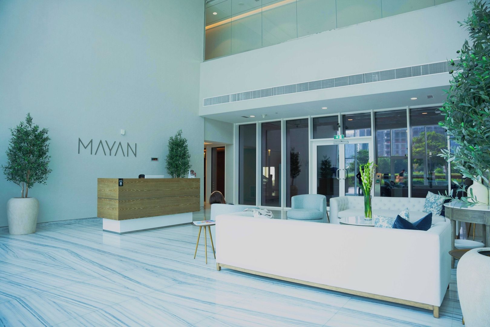 A modern reception area with a wooden reception desk, seating, and large windows.