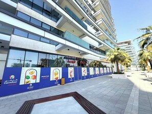 Monikerroksinen rakennus, jonka alakerrassa on Carrefour-supermarket. Rakennuksessa on suuret lasi-ikkunat ja sininen mainosbanneri.