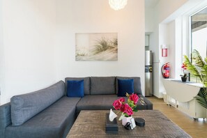 A modern living room with a grey sofa, a coffee table with decorative items, and a painting on the wall. - Luxury Jr. 1BR in Mayan Yas Island (Abu Dhabi)