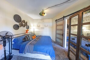 Un dormitori amb un llit, un ventilador, una làmpada i una paret decorativa.