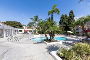 Une piscine entourée d’une terrasse, de palmiers et de chaises longues.