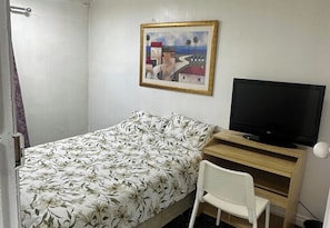 A room with a bed, a television on a wooden stand, a chair, and a painting on the wall. - 2-Bed House Sleeps 4 - Private Garden - Pets Ok (Middlesbrough)