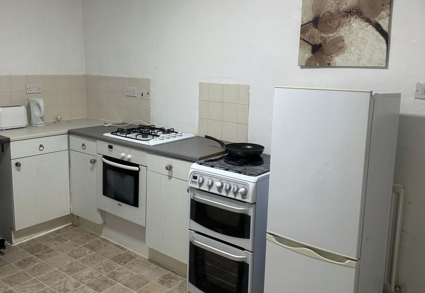 A compact kitchen with a gas stove, oven, and a refrigerator.