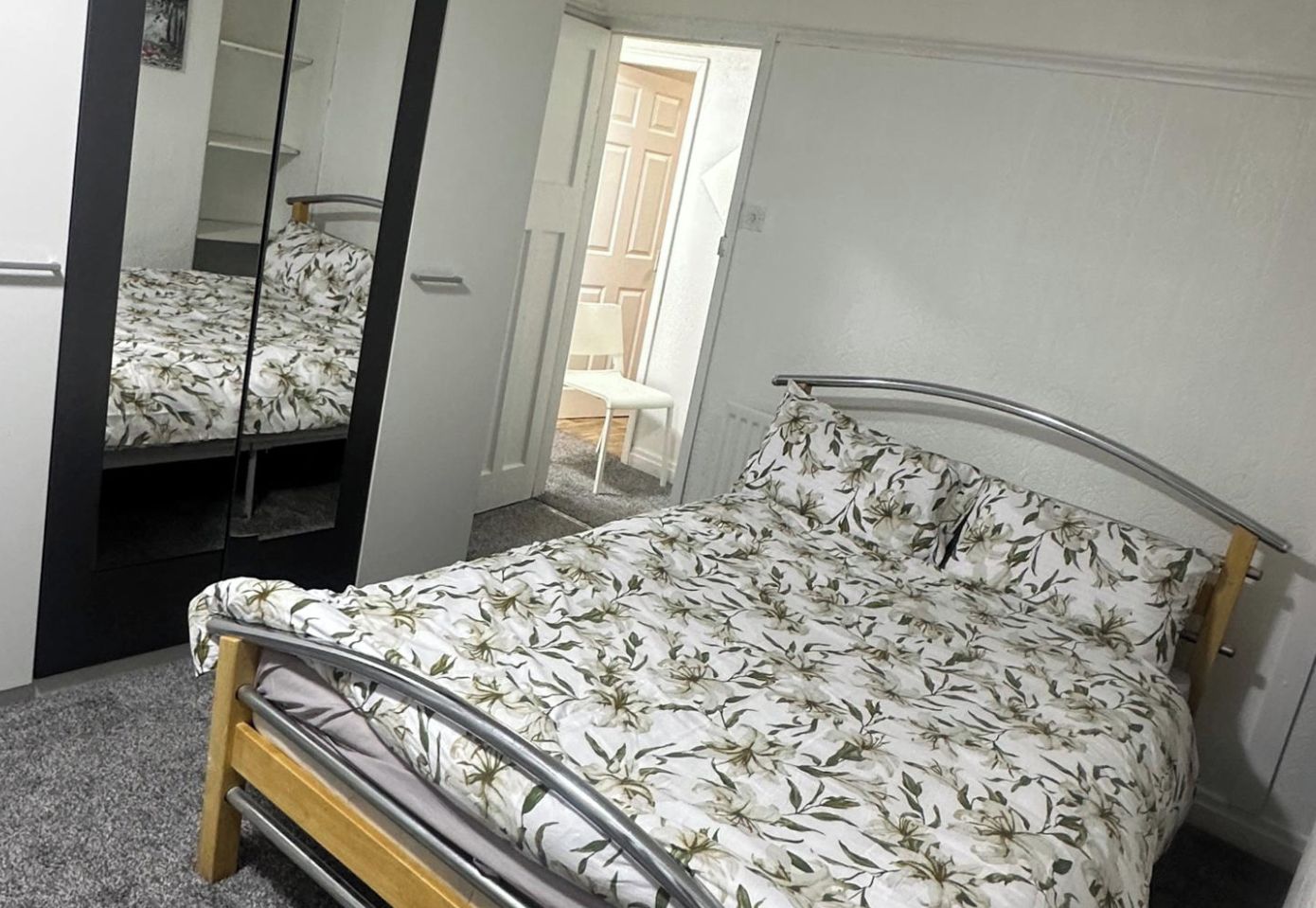 A bedroom with a bed, a mirror, and a door leading to a balcony.