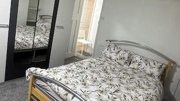 A bedroom with a bed, a mirror, and a door leading to a balcony.