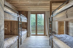 Una stanza con letti a castello, pavimento in legno e vista attraverso una porta vetrata.