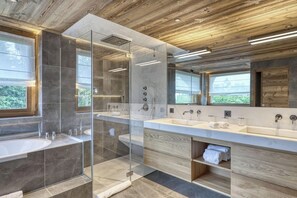 Un bagno moderno con una grande doccia vetrata, un mobile doppio lavabo e un soffitto in legno.