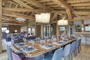 Un'ampia sala da pranzo con un lungo tavolo in legno apparecchiato per un pasto, circondato da sedie moderne.