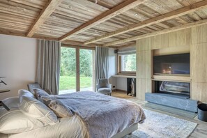 Une chambre à coucher avec un lit, une chaise, une cheminée et de grandes fenêtres.