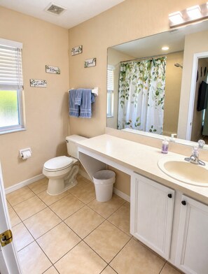 A bathroom with a toilet, sink, and shower curtain. - 4BR/3BA Disney Retreat Pool & Lazy River/Patio/ lFitness rm Near all attractions (Davenport)