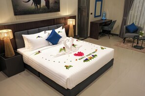 Een hotelkamer met een netjes opgemaakt bed, een bureau, een stoel en een lamp.