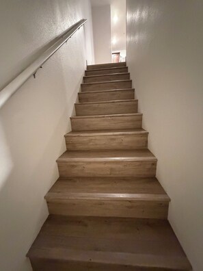 Eine Holztreppe mit einer Handläufe auf der linken Seite, die zu einer Zwischenebene führt.