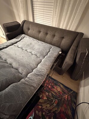 Ein Bett mit gemustertem Matratzenüberzug, einem Kopfteil und einem Nachttisch.