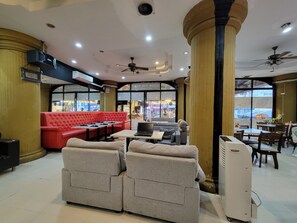 Un espace détente avec des canapés et des tables, un ventilateur de plafond et une vue sur la rue.