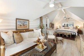 A cozy, rustic bedroom with a sloped ceiling, a large window, and a bed with a leopard print throw. - Sedona Desert Sactuary: Boho-Chic Cabin for 16 on one acre with Red Rock Views (Sedona)