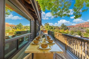 A dining area with a table set for six, overlooking a scenic landscape. - Sedona Desert Sactuary: Boho-Chic Cabin for 16 on one acre with Red Rock Views (Sedona)